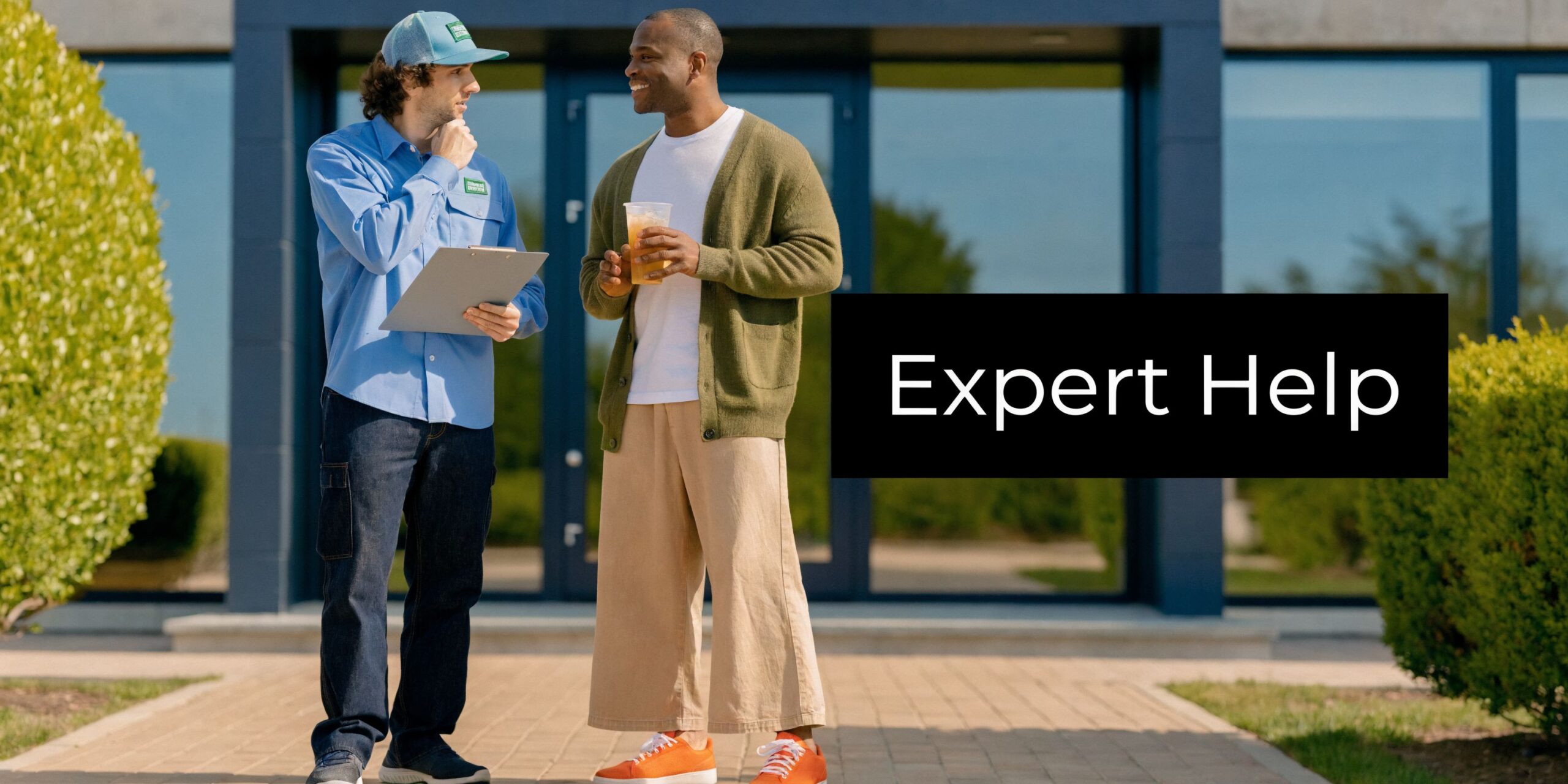 A service worker in a blue uniform and cap talking to a client about pest control services.