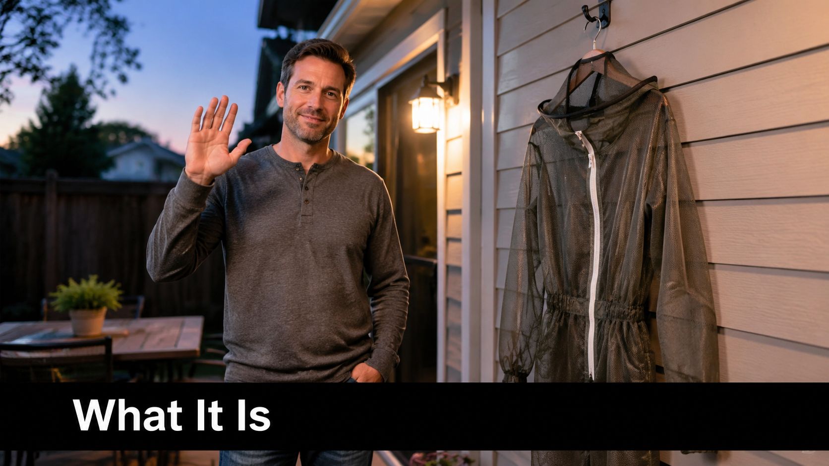 A man waves in front of his house next to a mesh mosquito net suit hanging outside.